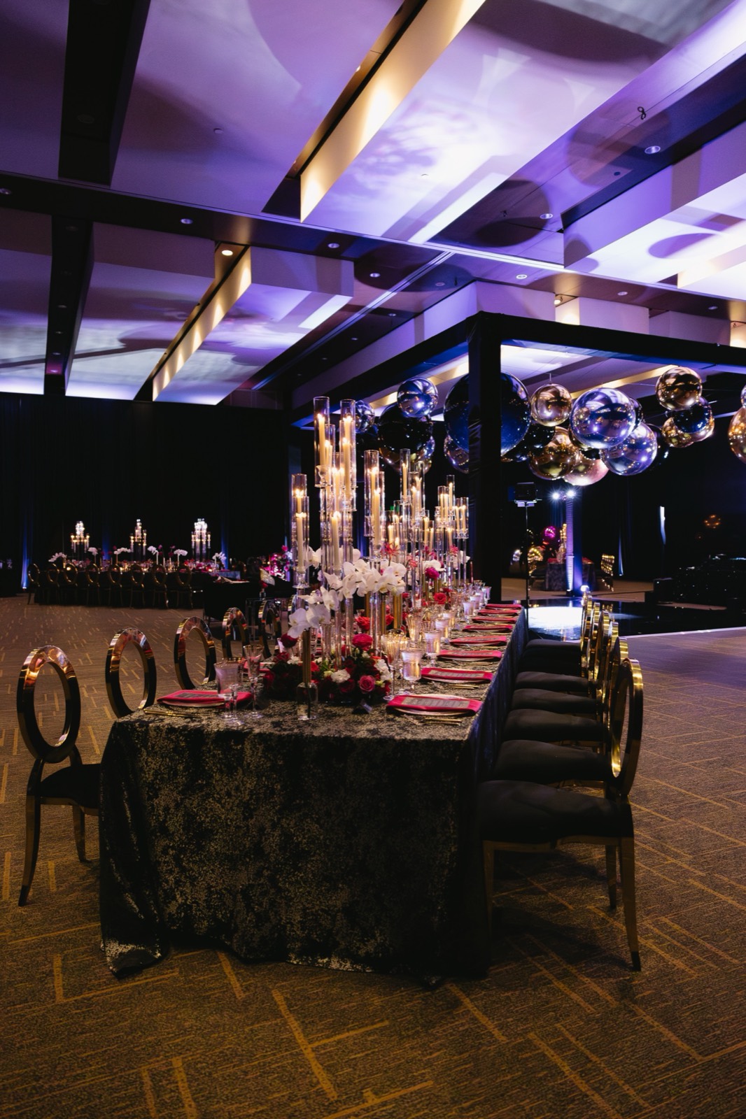 Dramatic reception lighting with black linens, candlelight, and reflective decor