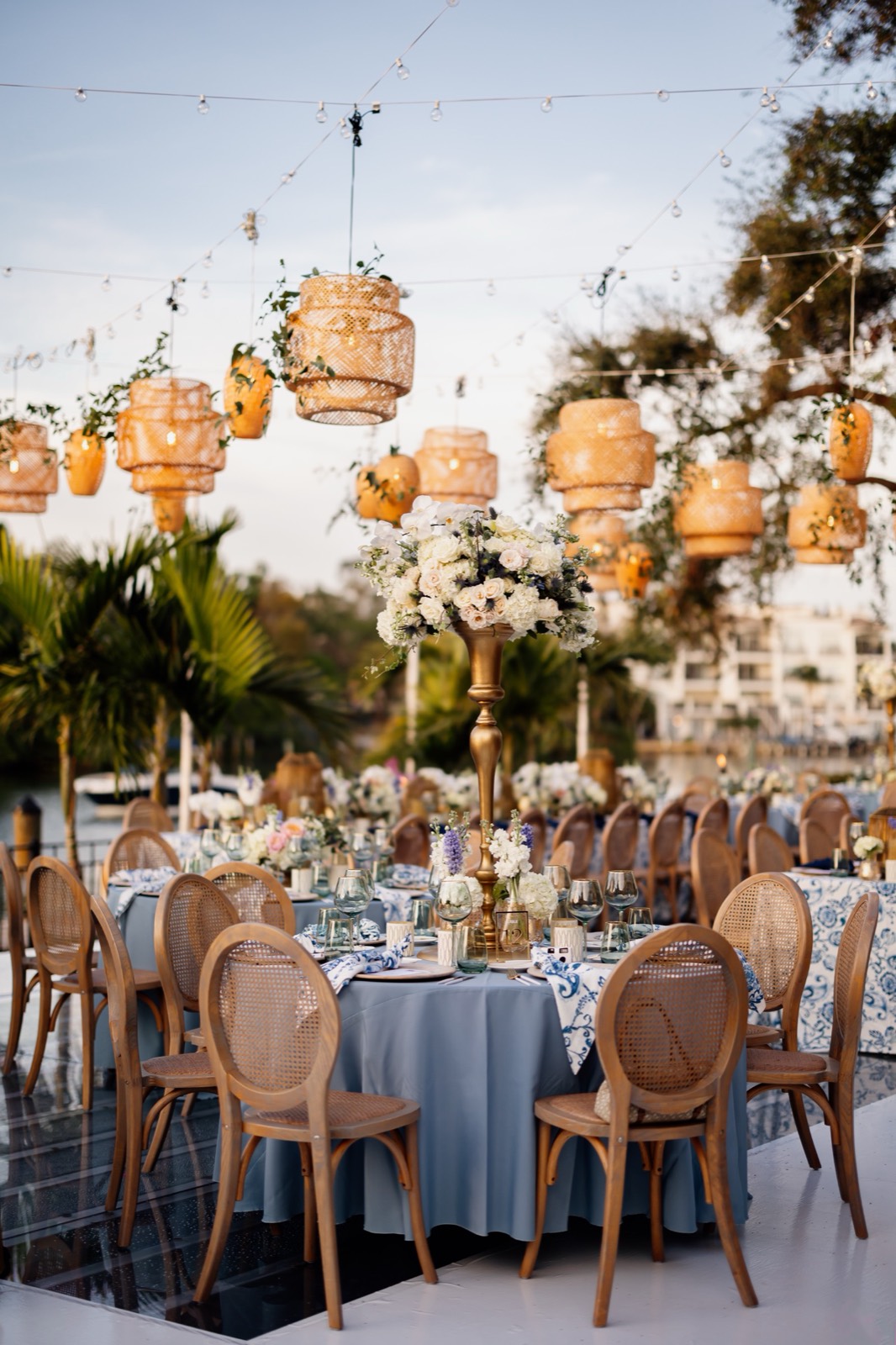 Outdoor waterfront reception table with woven lanterns and cane-back chairs