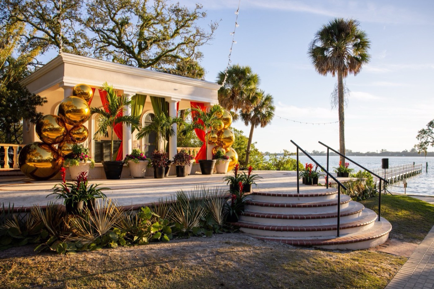 Waterfront event entrance with tropical draping and gold balloon installations